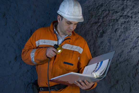 A mining engineer holding a notebook and flashlight