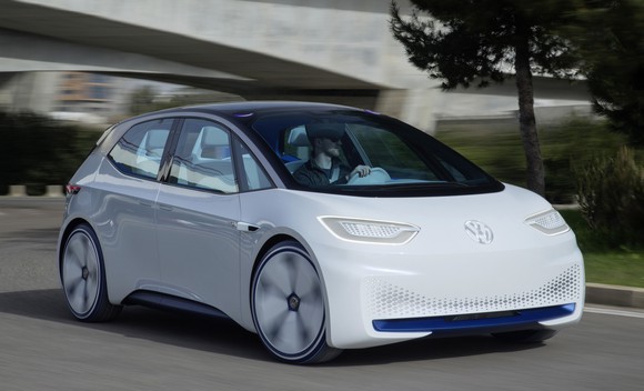 The Volkswagen I.D. Concept, a futuristic-looking white hatchback with a black roof, on a road.