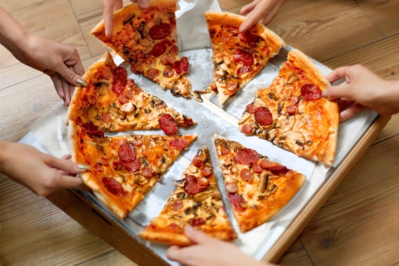 Pizza being taken from a pizza box.