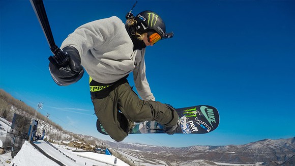 A snowboarder holding a GoPro camera on a stock while wearing one on his head.