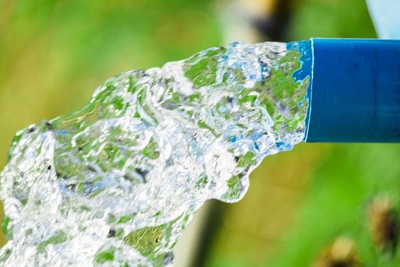 Water pouring out of a blue plastic pipe.