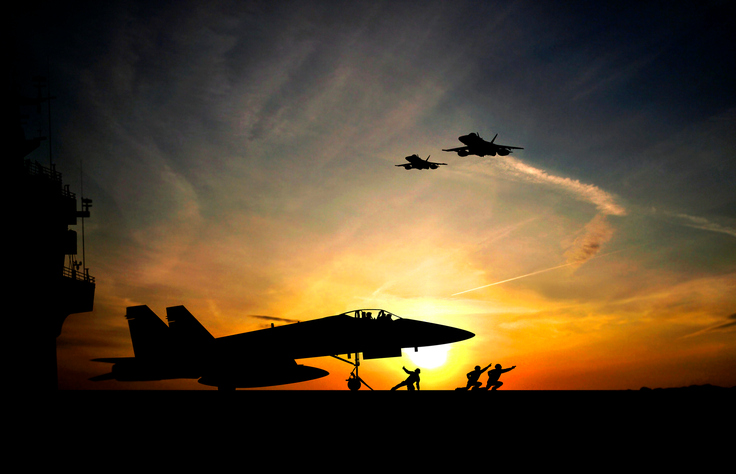 Jet taking off from aircraft carrier at sunset.