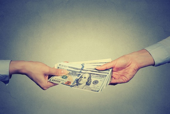 Cash is being handed between two people.