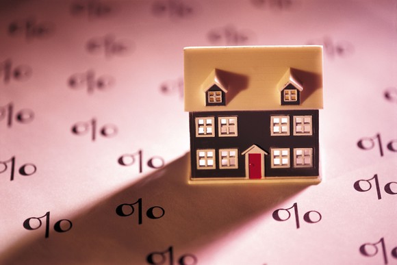 A toy house sits on a paper with percentage signs