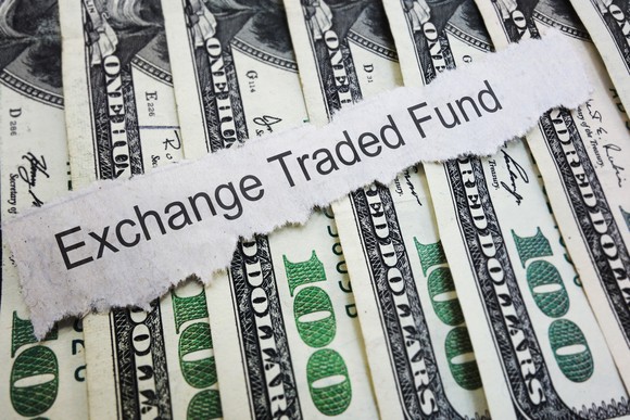 The words "Exchange Traded Fund" typed on top of a spread-out stack of $100 bills