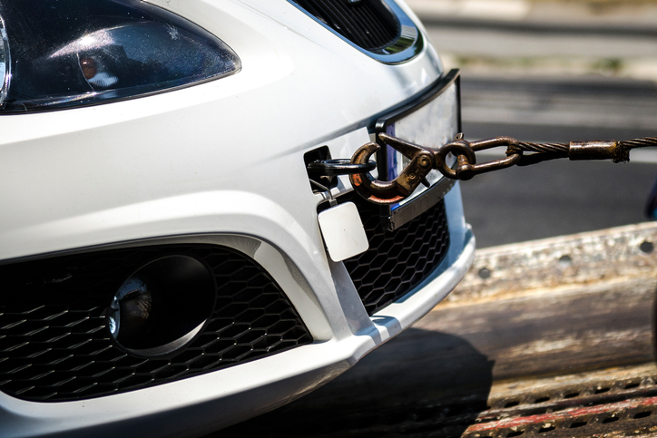 White sports car being towed with close-up of metal towing hitch.