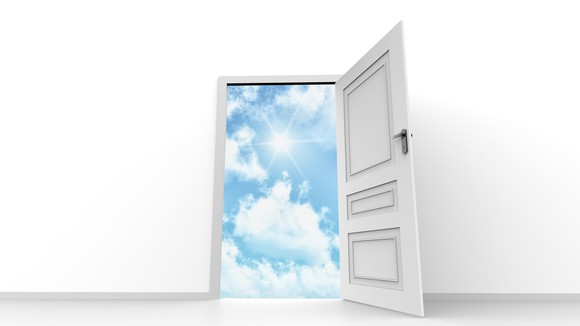 Door open with blue sky and sun shining through clouds