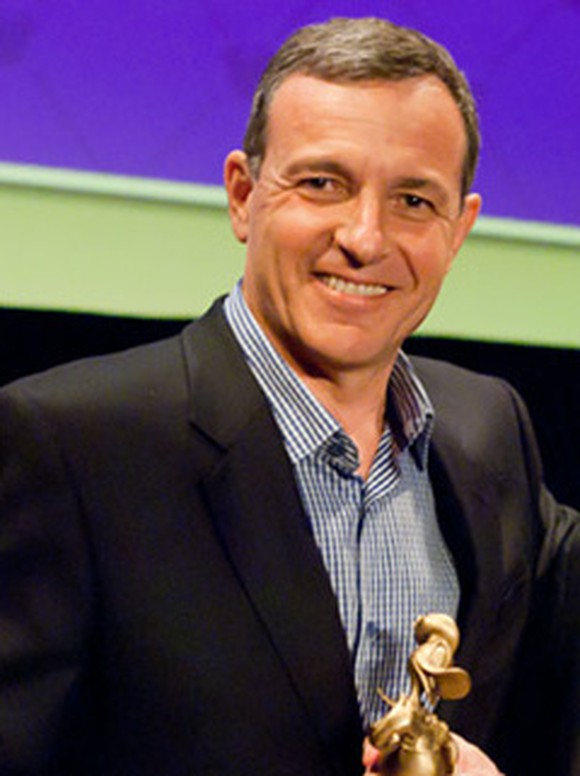 Disney CEO Bob Iger, smiling and holding a gilded Donald Duck statuette.