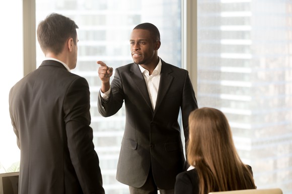 Professionally dressed man pointing a finger angrily at another professional man