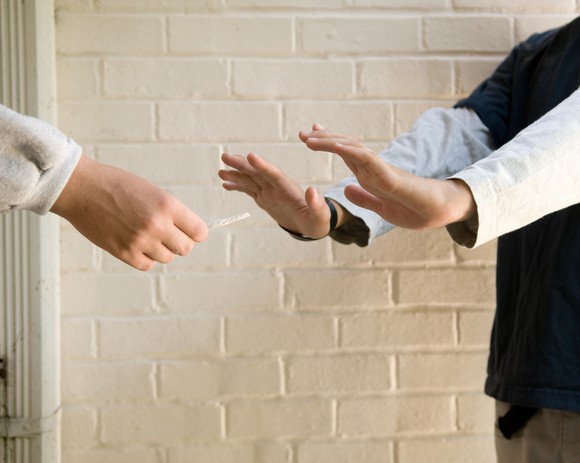 A person with a cannabis joint being told "no" by a teenager.