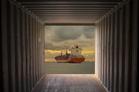 A cargo container ship sailing out of view from a cargo container.