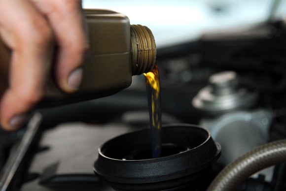 A hand pouring motor oil into a car's engine