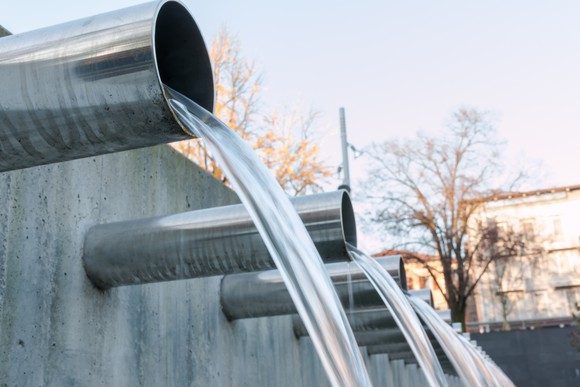 Water flowing from drain pipes through a concrete wall.