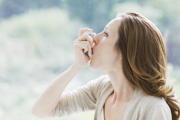 A woman with asthma using a rescue inhaler.