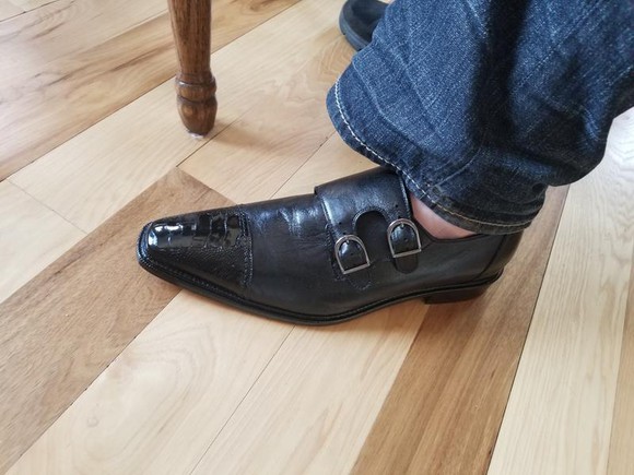 Pictured from about the knee down is a denim-clad leg and a sockless foot in a man's shoe