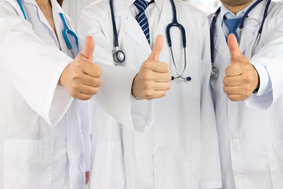 Three doctors giving a thumbs-up sign.