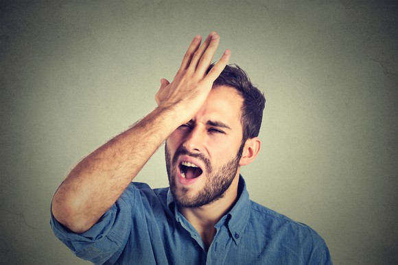 Man holding hand to forehead and grimacing