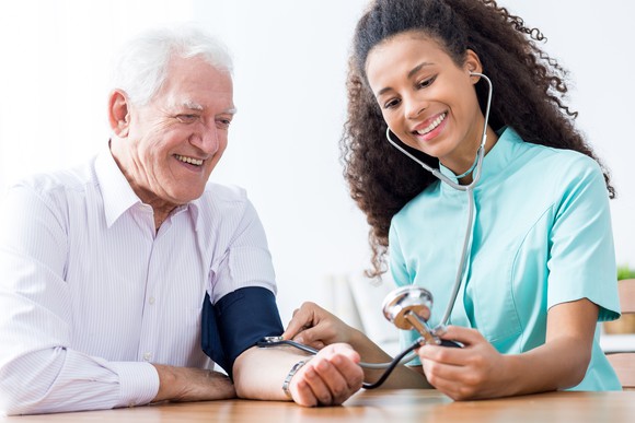 A nurse takes the blood pressure of an older man.