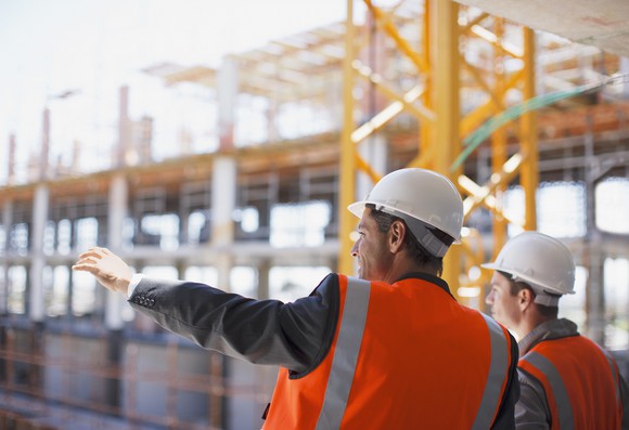 Two construction workers oversee a work project.