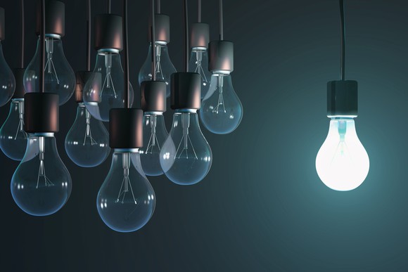 bright light bulb shining near group of unlit bulbs