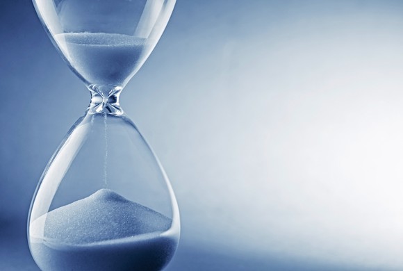 hourglass with white sand against blue background