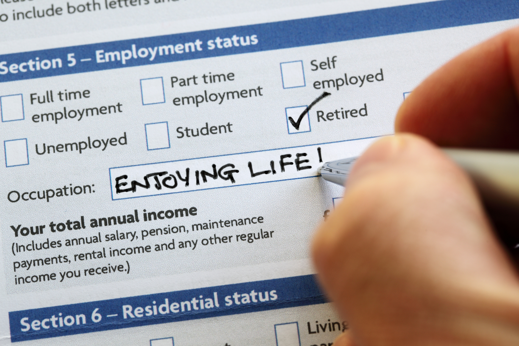 A person writing "enjoying life" and checking the retired box for employment status paperwork.