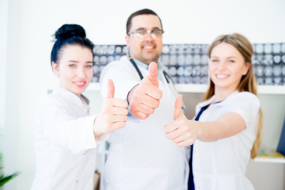 Three doctors making thumbs up gesture.