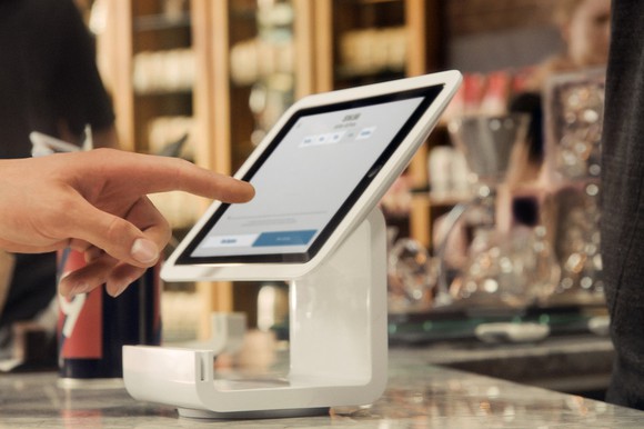 A hand on a Square Stand POS system.