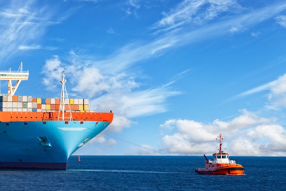 A tug boat pulling a much larger container ship.