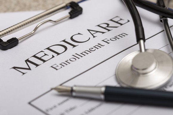 A Medicare enrollment form, stethoscope, and a pen.