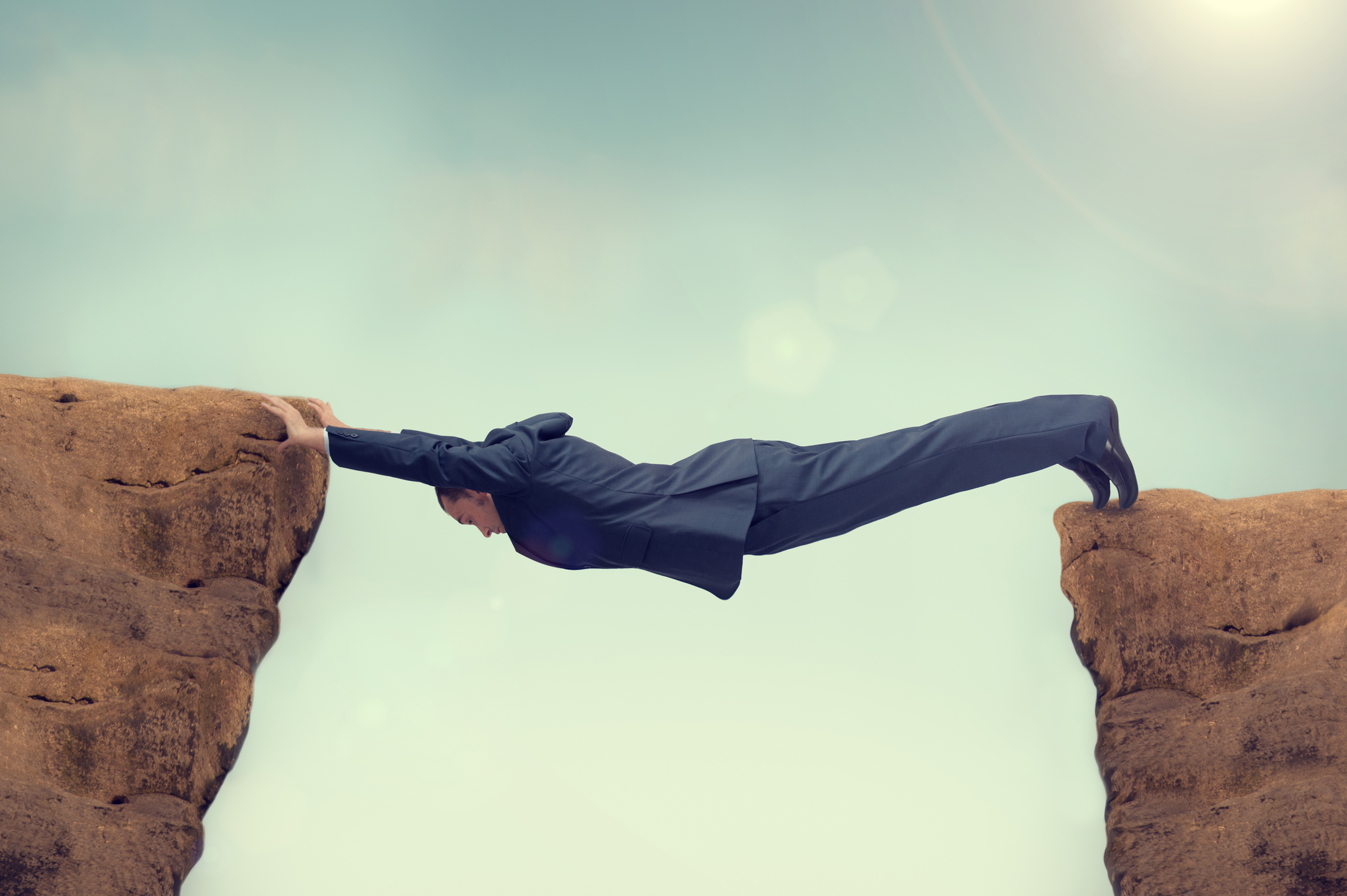 A person forms a bridge between two rock outcroppings.