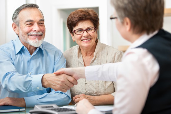 A retired couple shake hands with a counselor.
