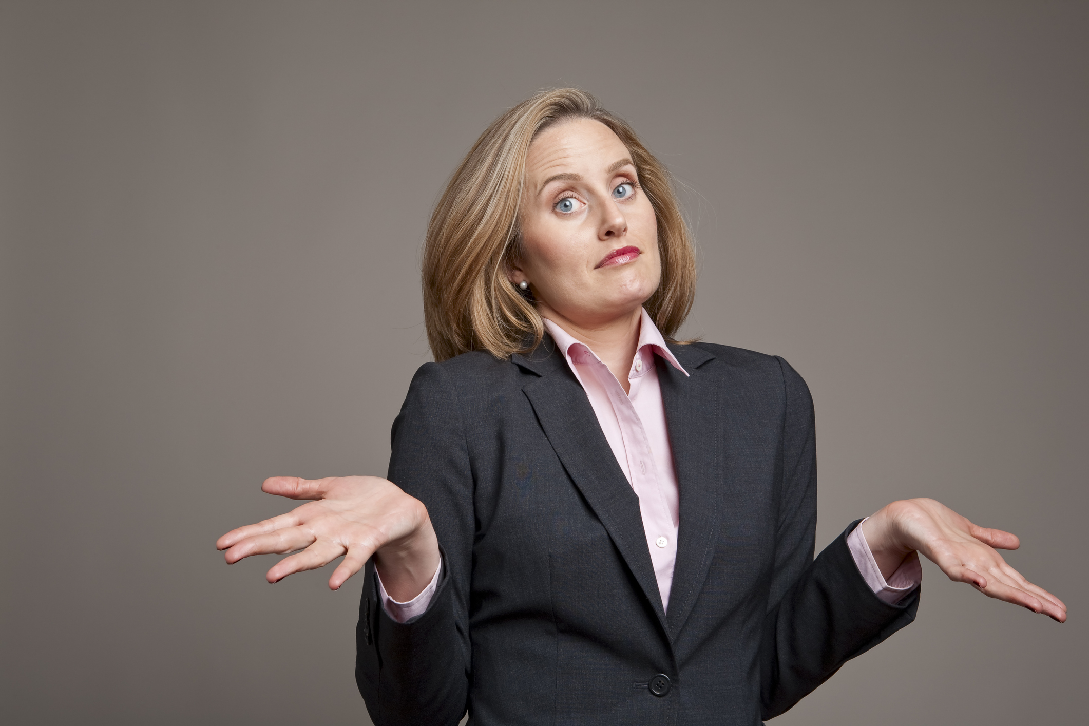 A businesswoman shrugs with a confused look on her face.
