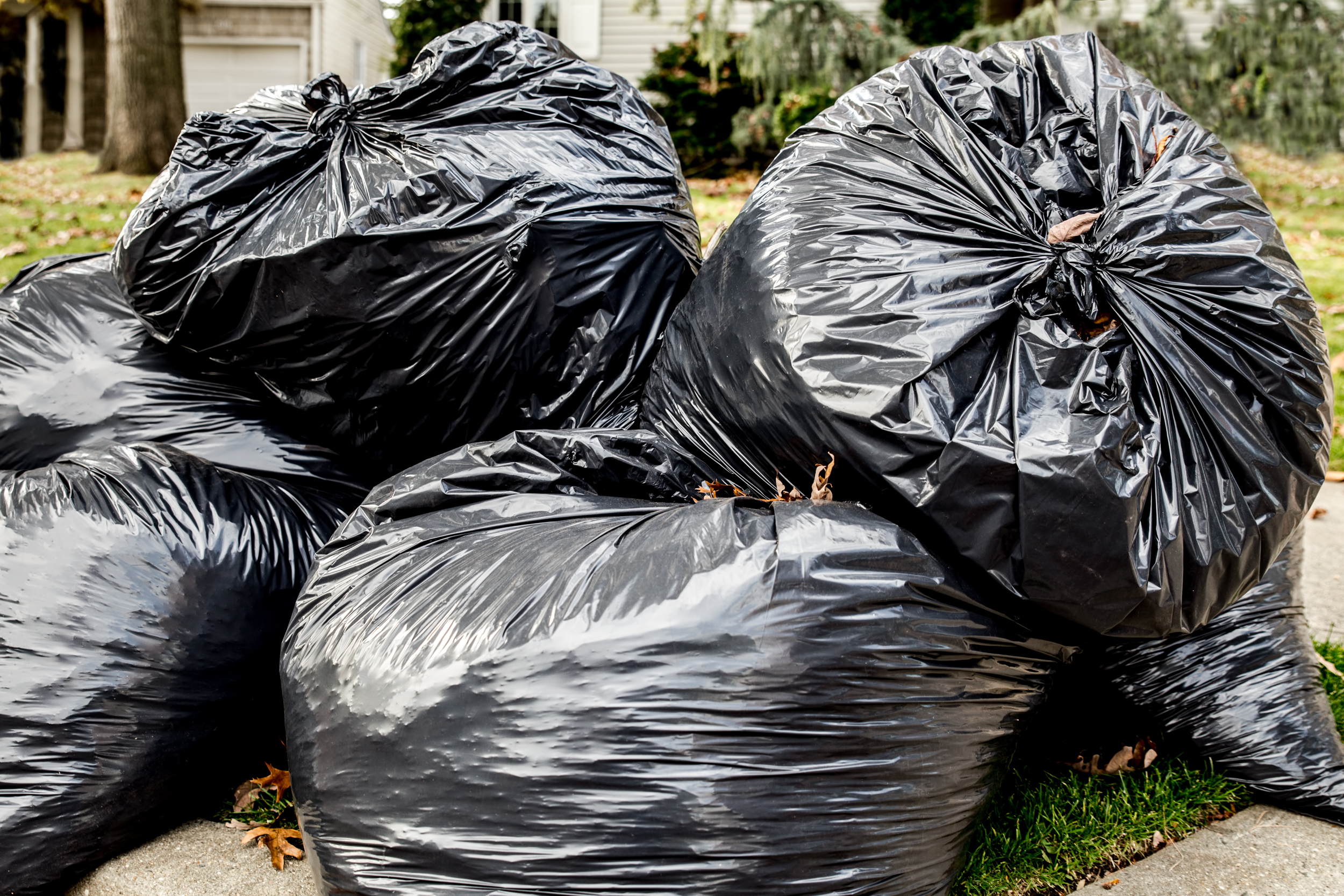 Filled up garbage bags near the curb.