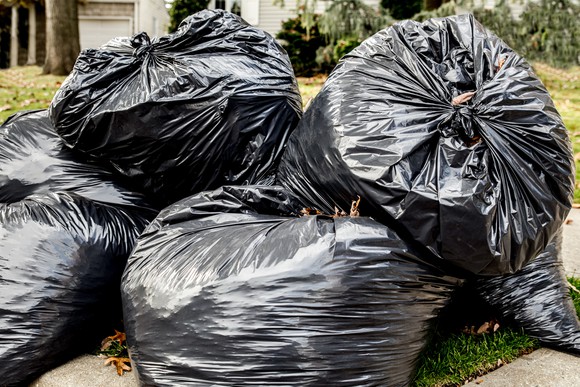 Filled up garbage bags near the curb.