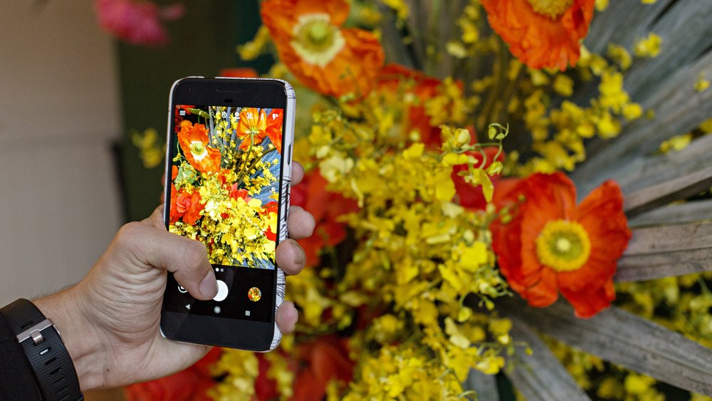 A man takes a photo with a Google Pixel smarphone.