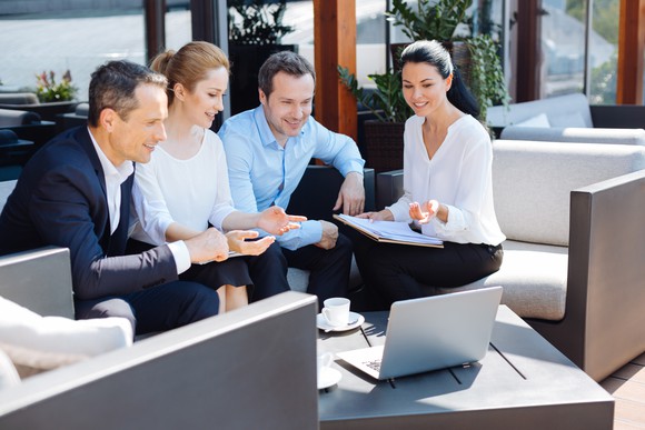 A group of young men and women discussing a presentation on a laptop.