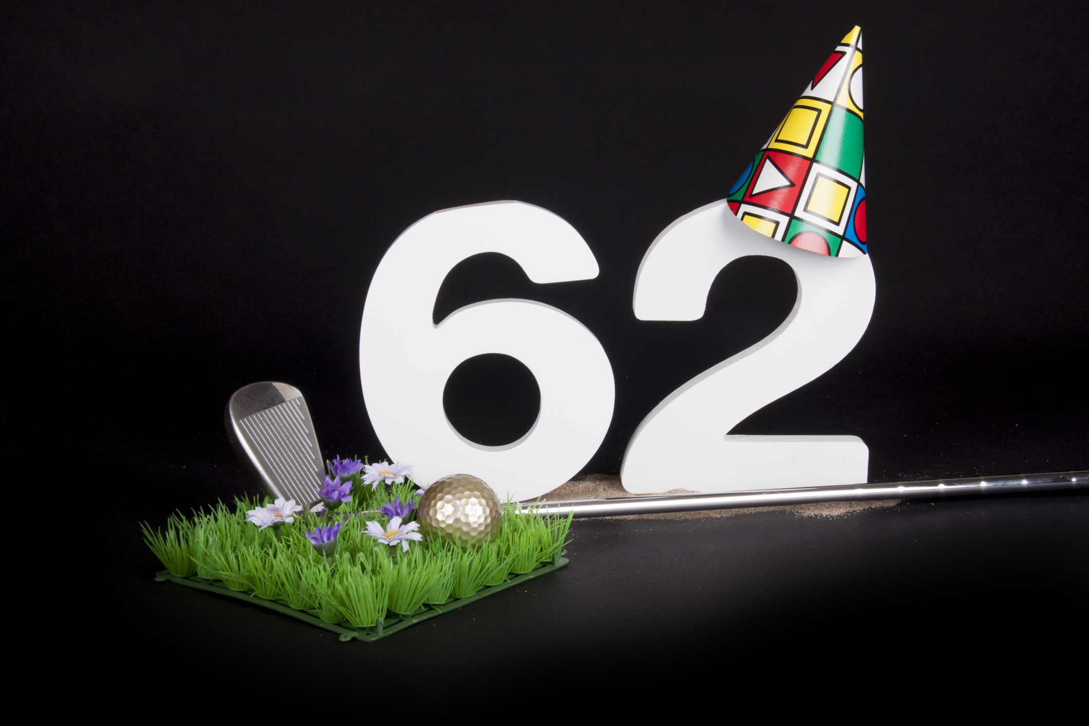 the number 62 with a party hat on and next to a golf club and a patch of grass