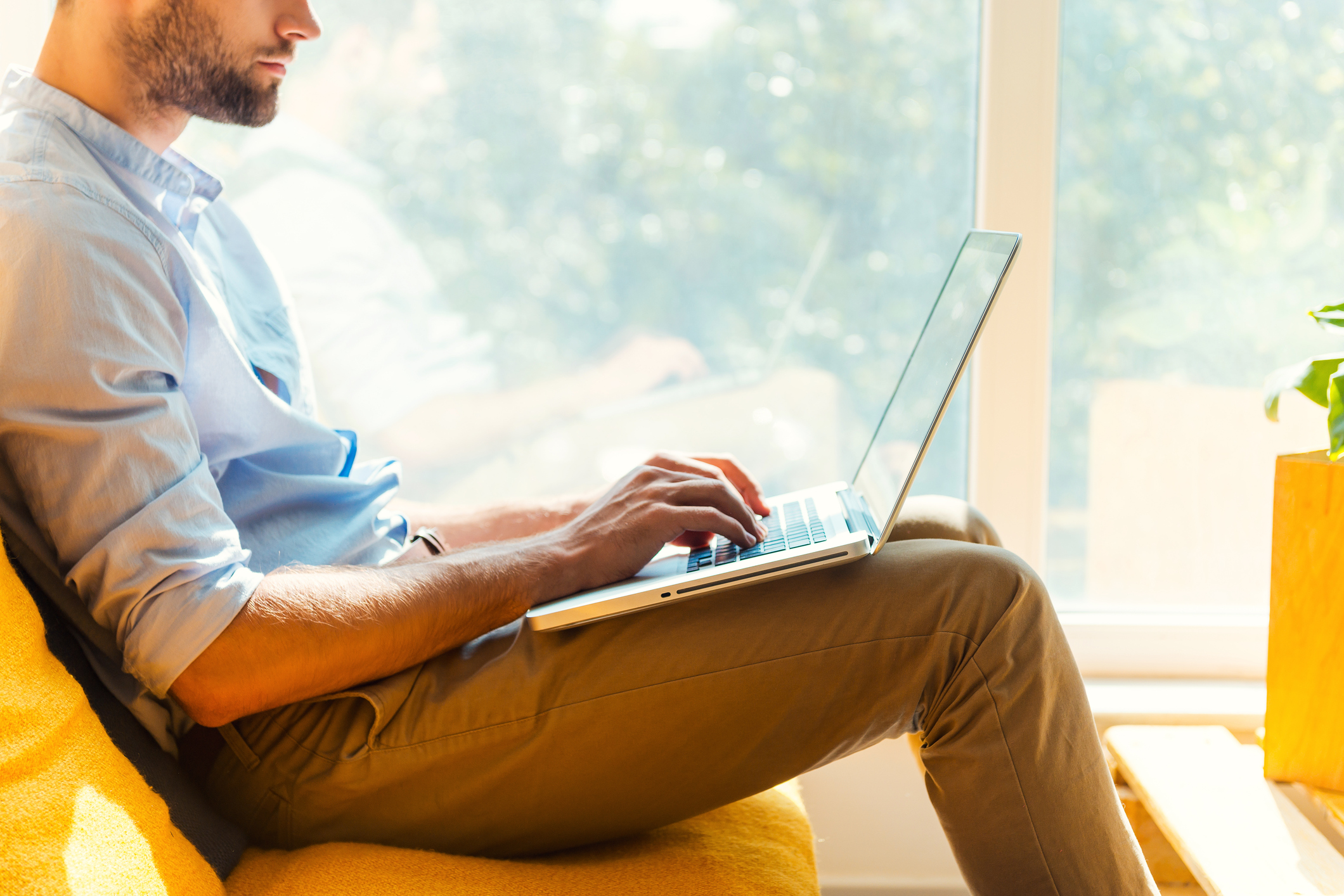 A man works on a laptop from a coucb
