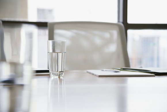A glass of water sits in front of an empty chair