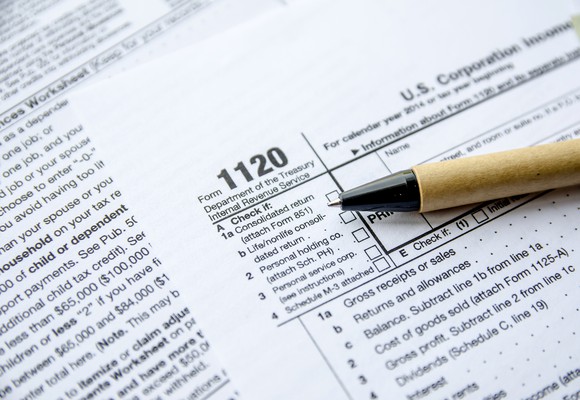 Tax Form 1120 for corporate income tax with a pen lying on top.