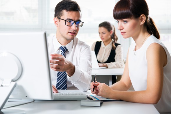 Man showing woman something on his computer screen