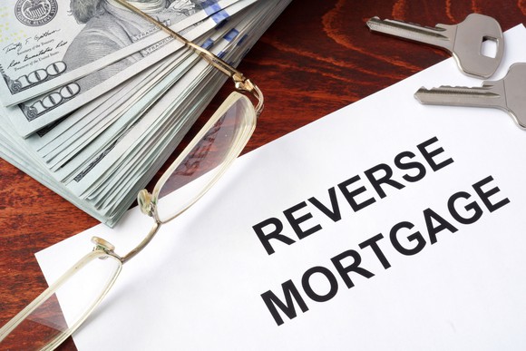 Reverse mortgage paperwork on a table with keys and a stack of money.