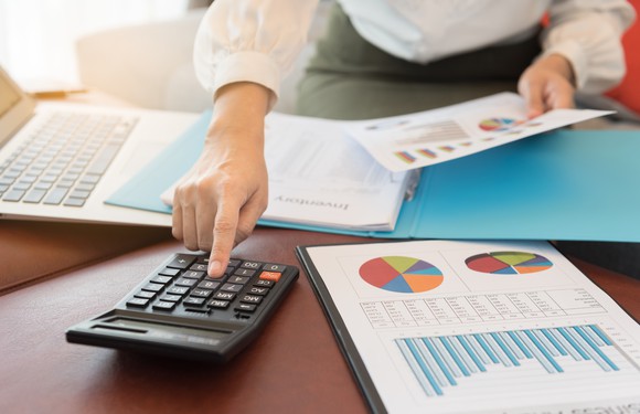 Man using calculator and reviewing business documents