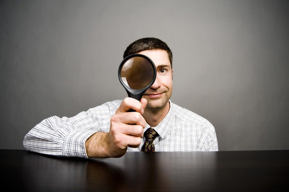 Man looking through big magnifying glass