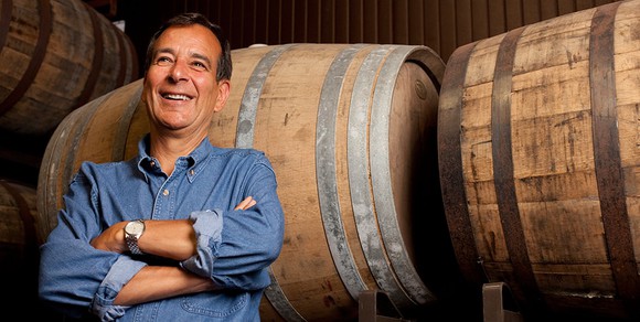 Boston Beer founder Jim Koch standing in from of some beer barrels.