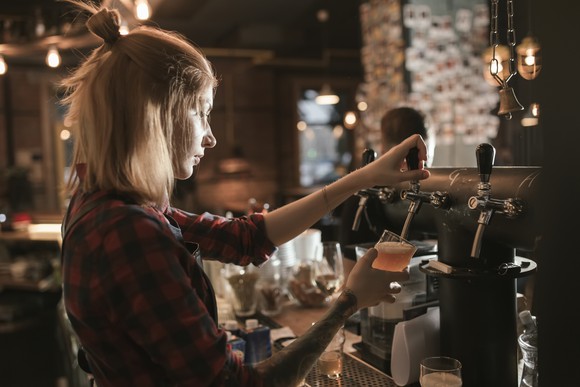 A female bartender pouring a beer.