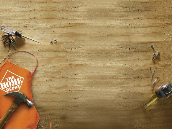 A Home Depot apron and various tools resting on a piece of wood.