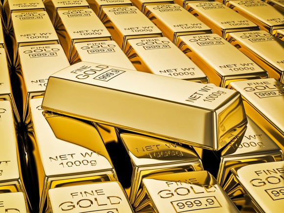 A gold bar lying atop a stack of gold bars.