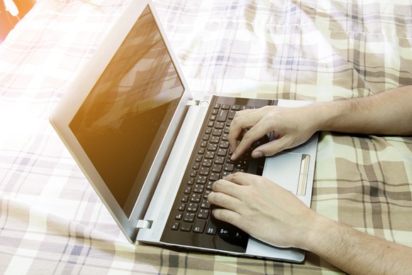 Typing on laptop in bed